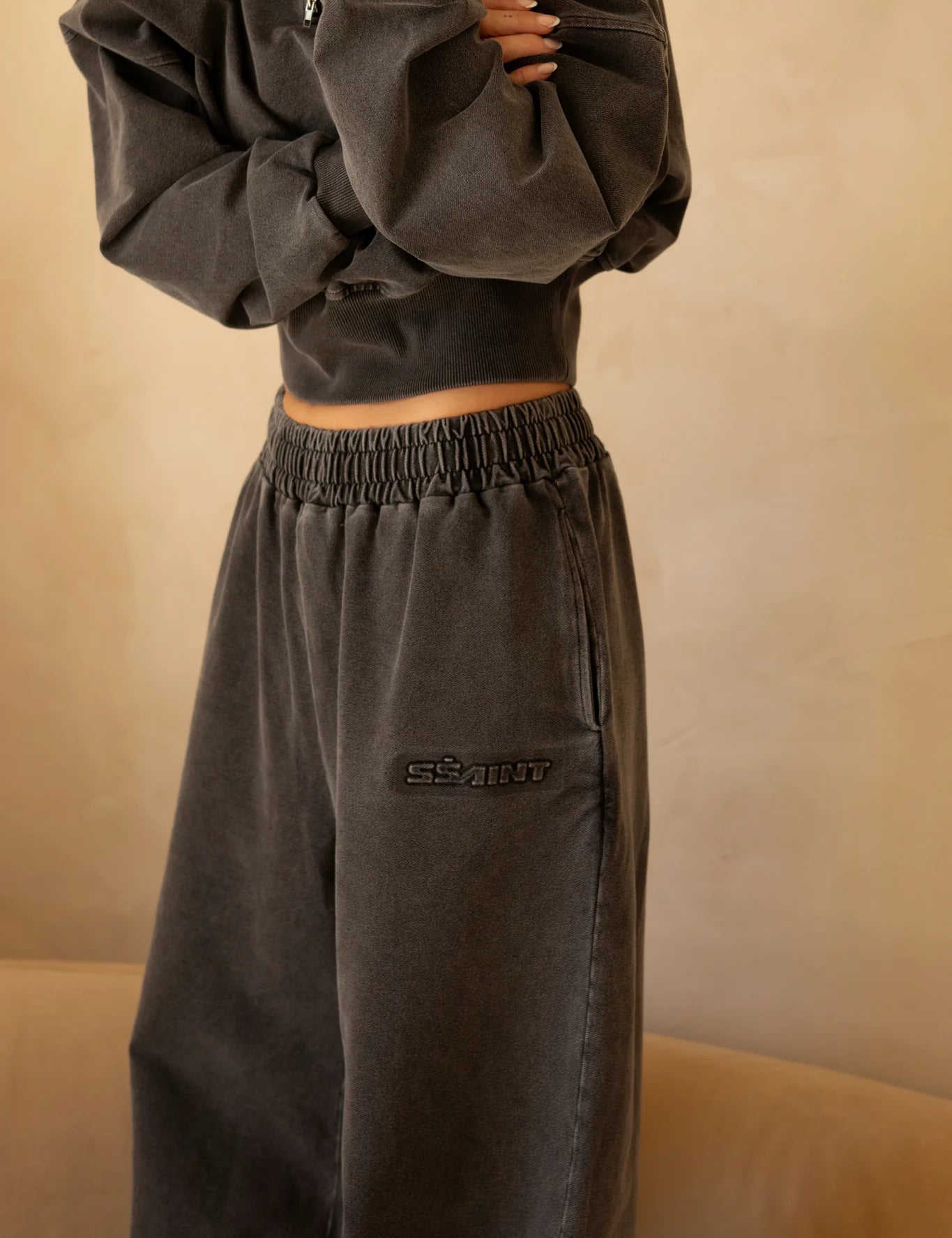 Close-up of charcoal acid-wash wide-leg pants with embroidered logo detail