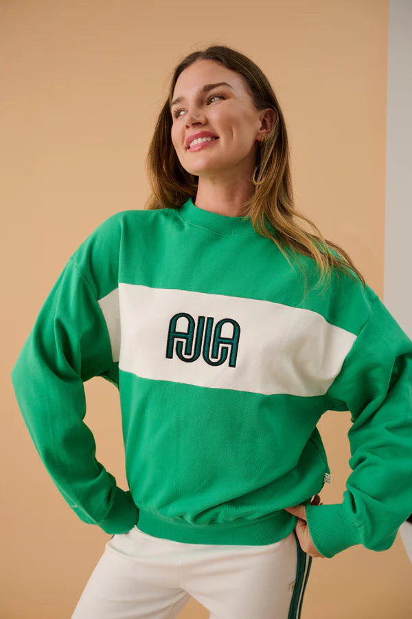 Woman wearing a green sweatshirt with a logo on a beige background