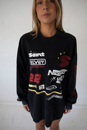 lose up of SSAINT Signature Moto Tee graphic print and fragrance artwork in Black Acid Wash