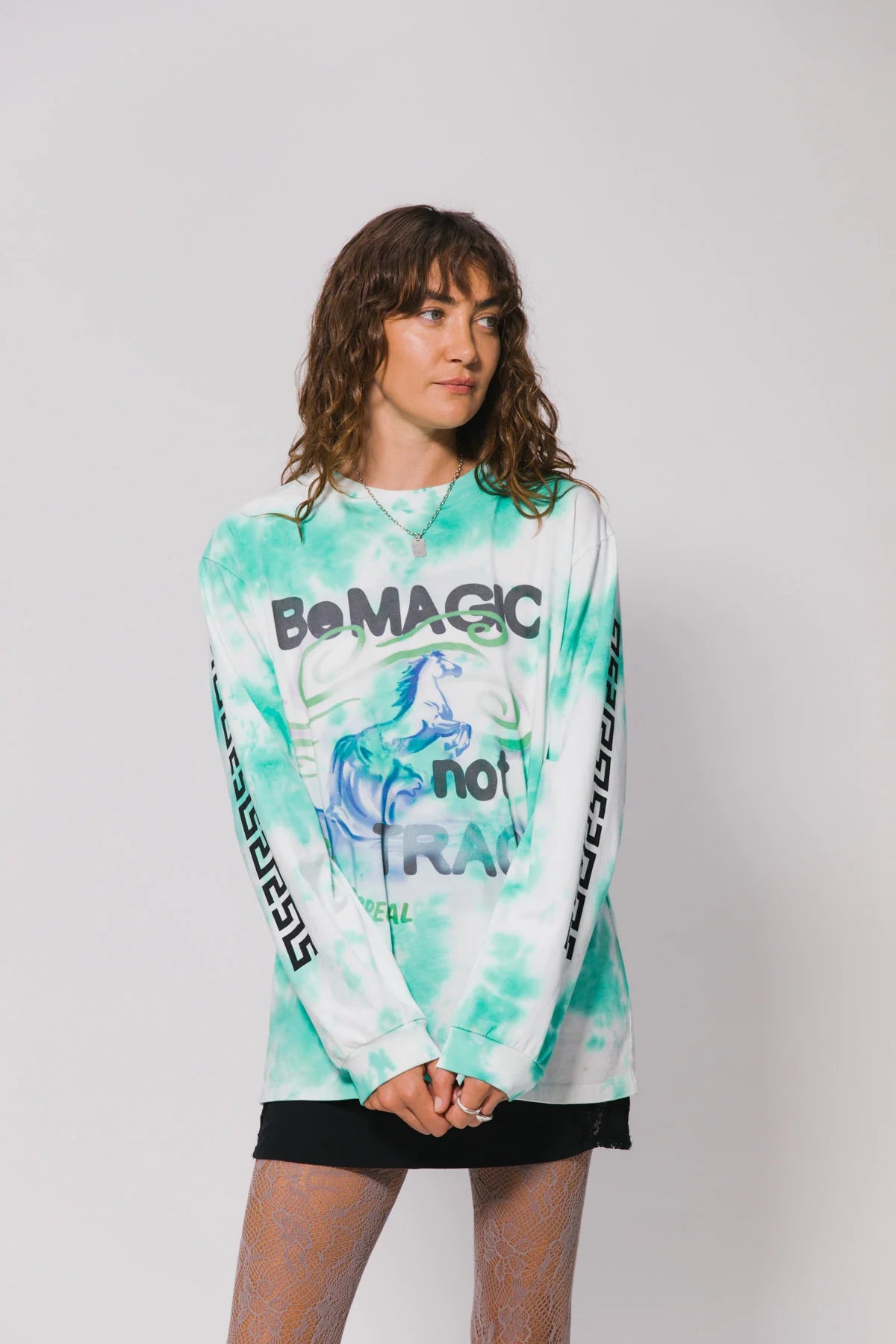 Person wearing a tie-dye long-sleeve shirt with text on a plain background