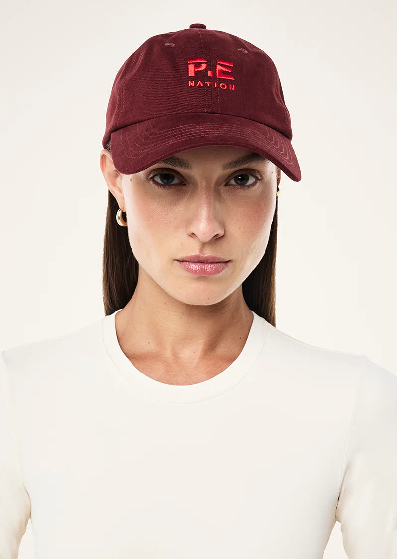 Model wearing P.E Nation Heads Up Cap in Cabernet and Strawberry casual styling