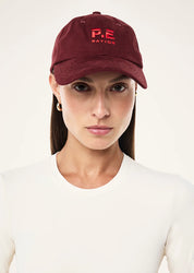 Model wearing P.E Nation Heads Up Cap in Cabernet and Strawberry casual styling