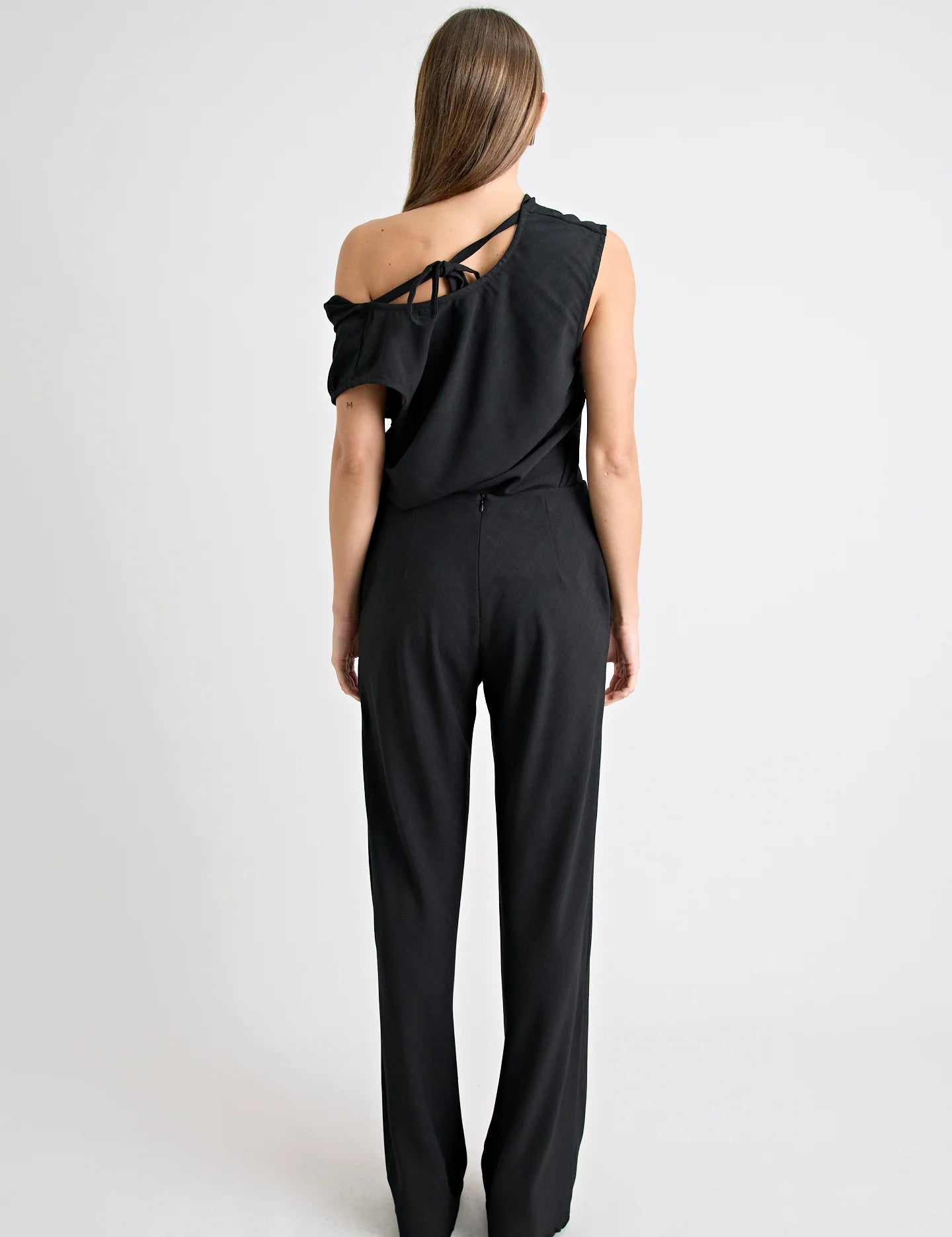 Black one-shoulder jumpsuit worn by a model on a white background