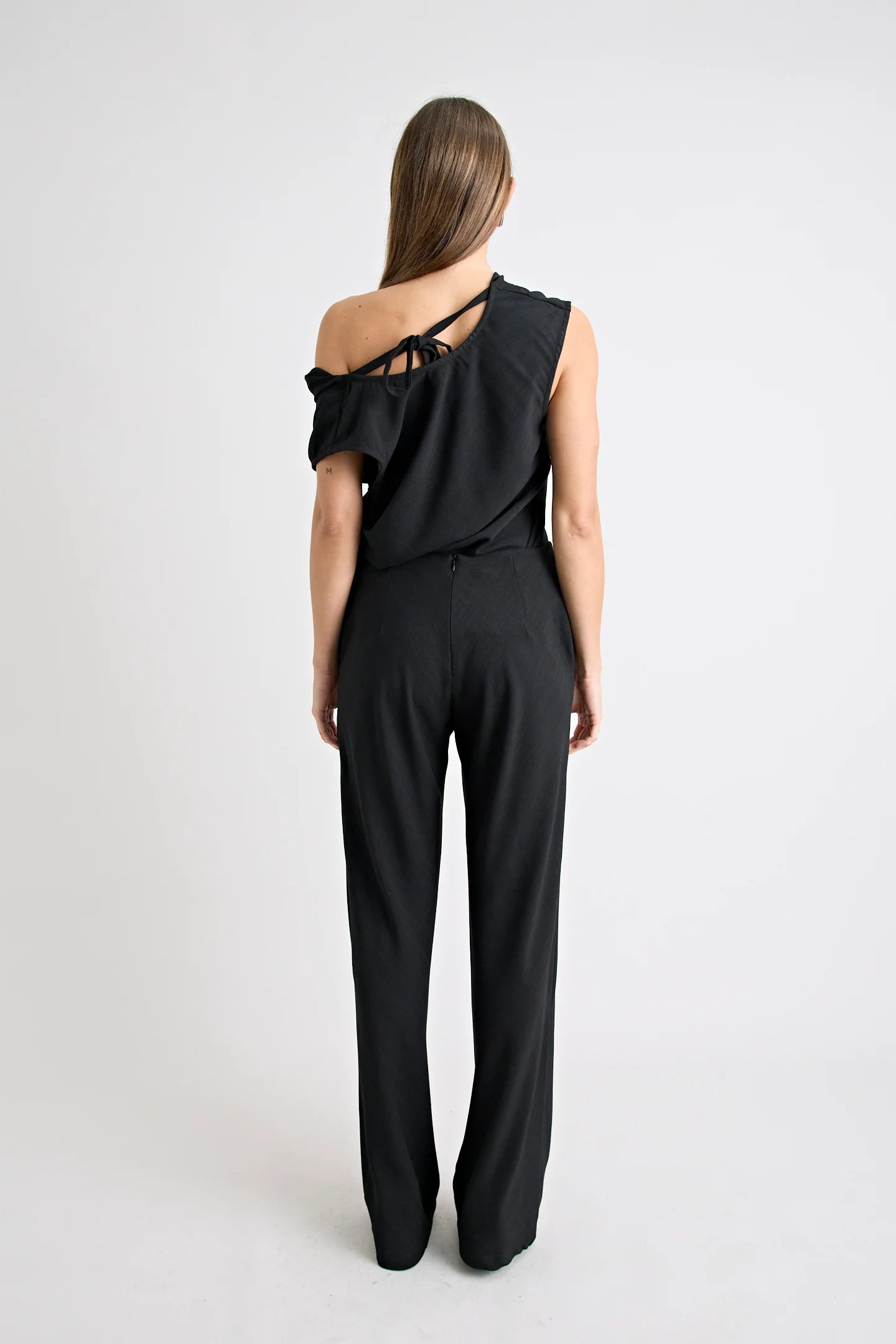 Black one-shoulder jumpsuit worn by a model on a white background