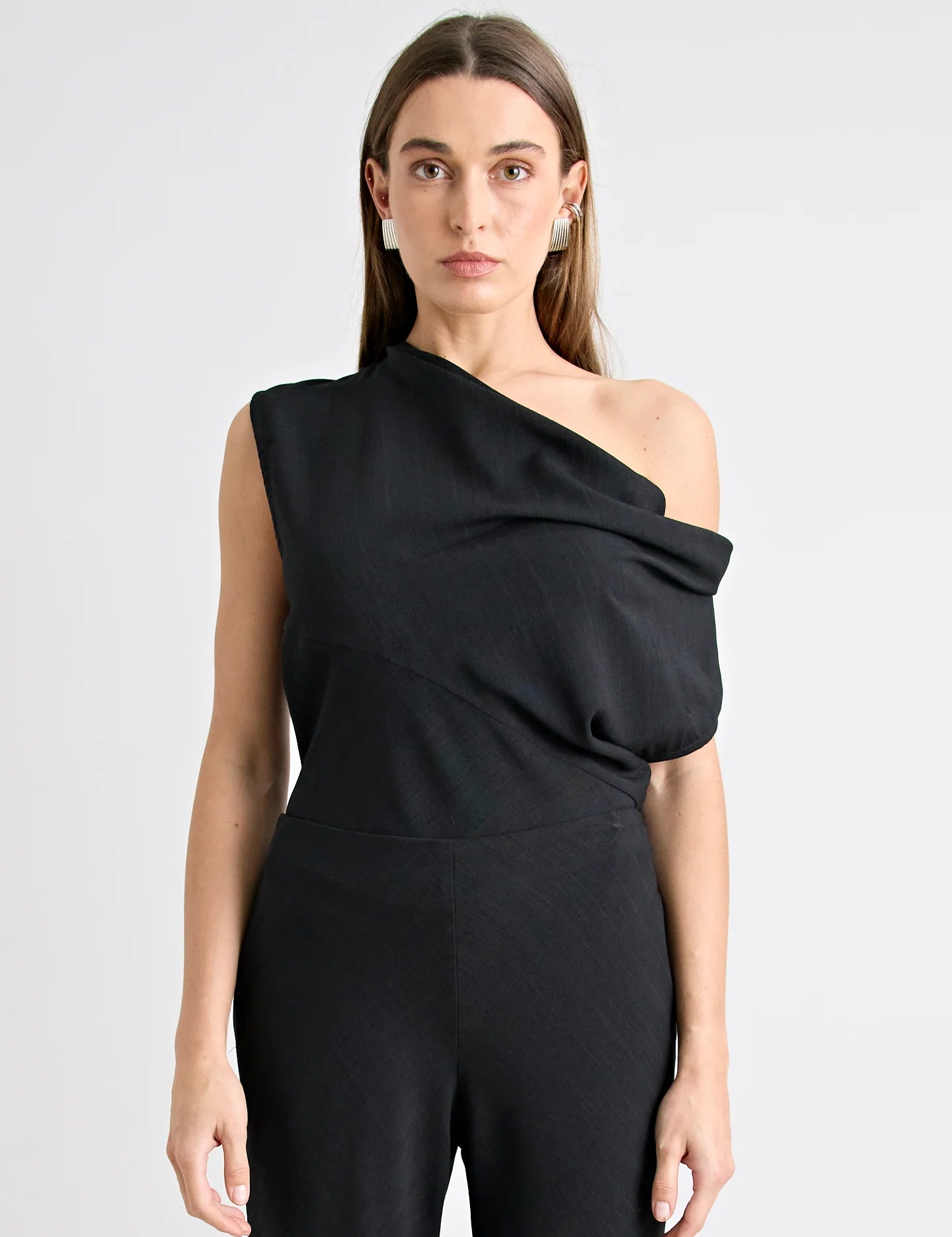 Woman wearing a black one-shoulder jumpsuit on a white background