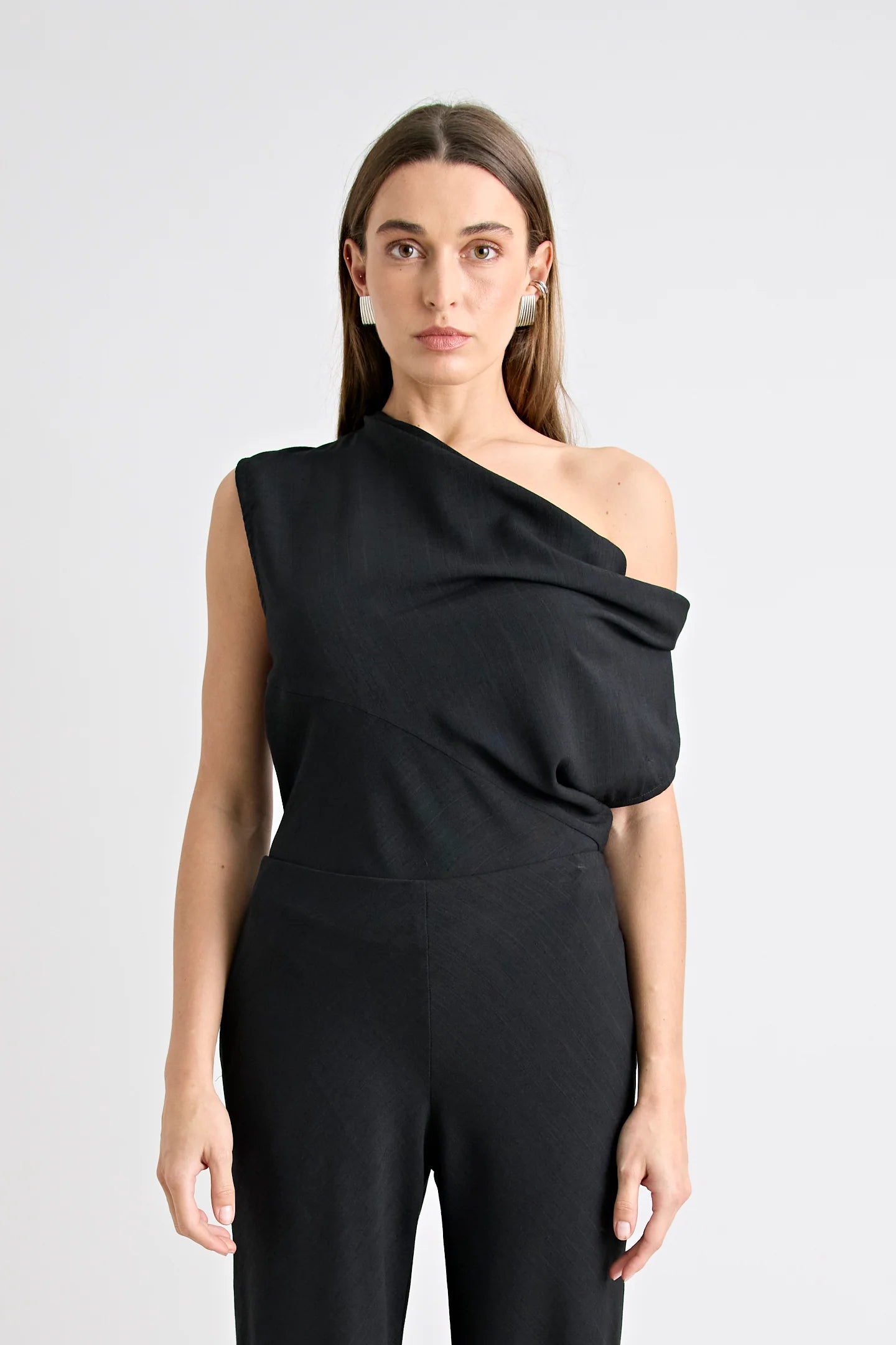 Woman wearing a black one-shoulder jumpsuit on a white background