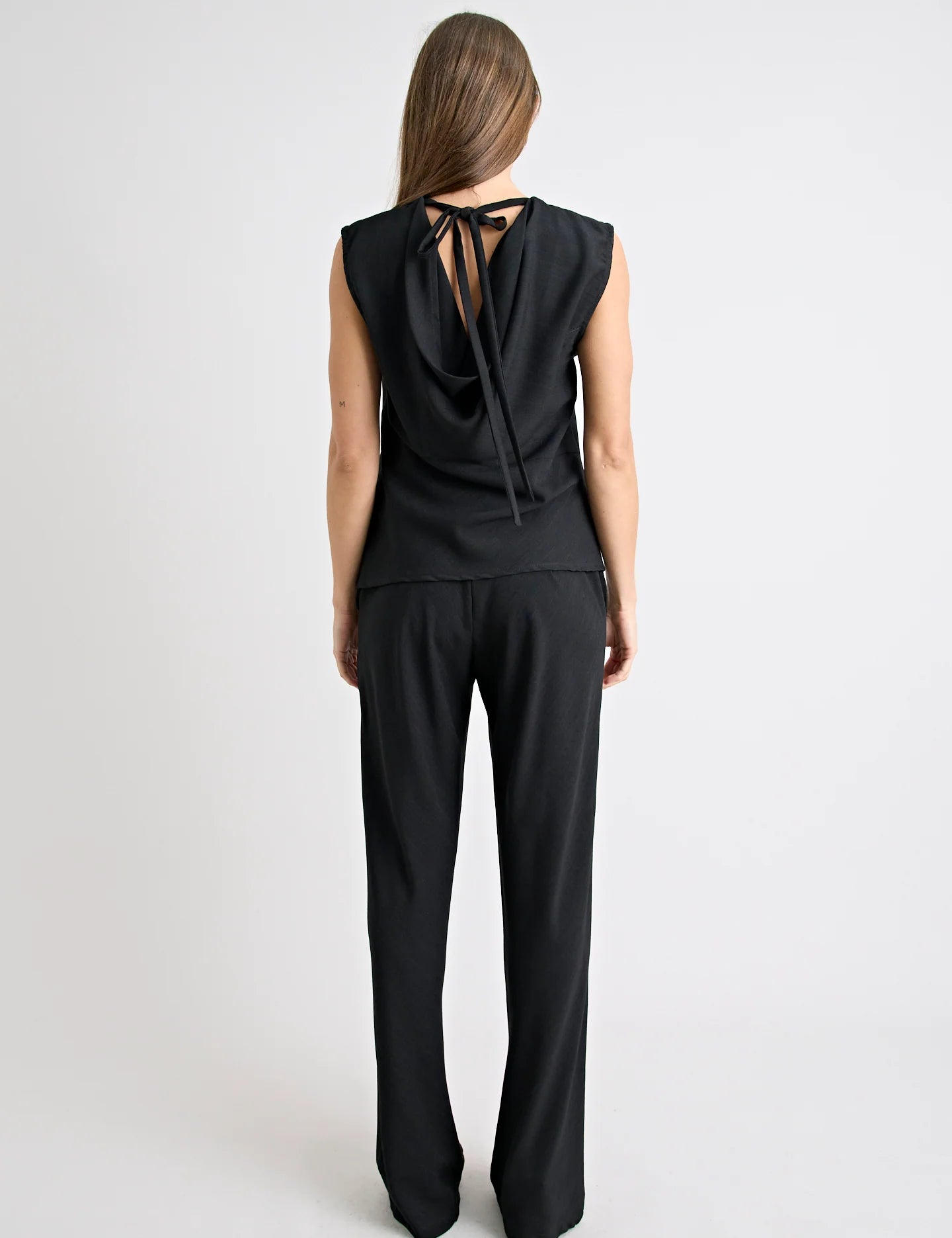Person wearing a black sleeveless top and pants on a white background
