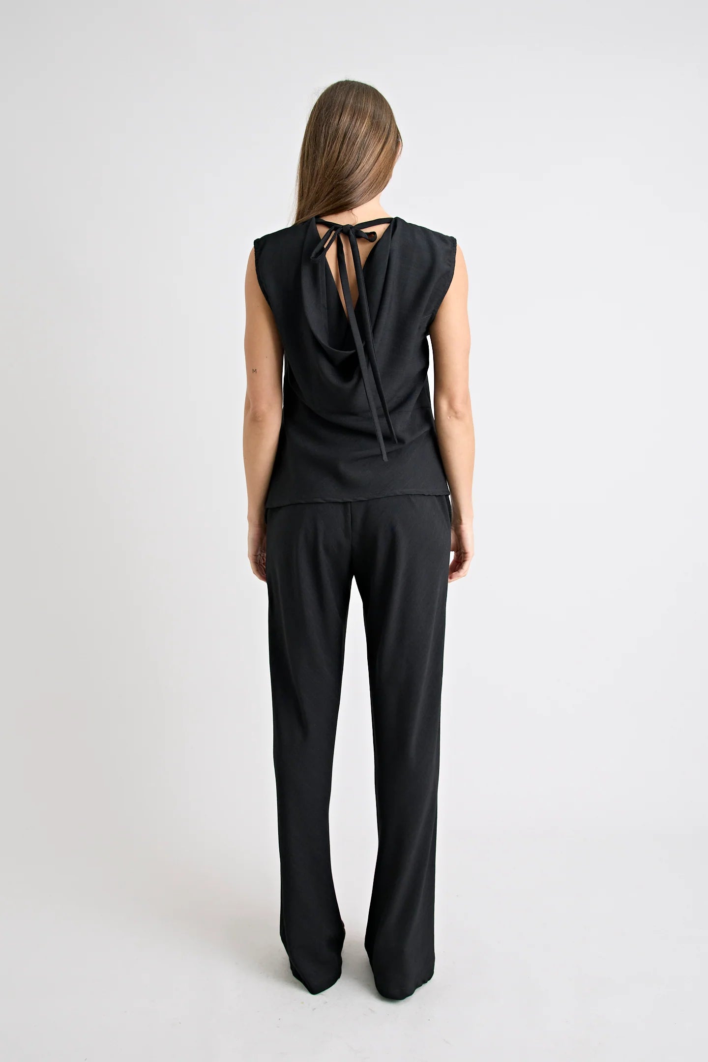 Person wearing a black sleeveless top and pants on a white background