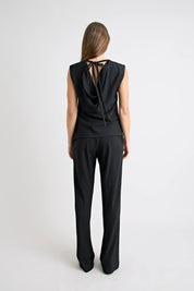 Person wearing a black sleeveless top and pants on a white background