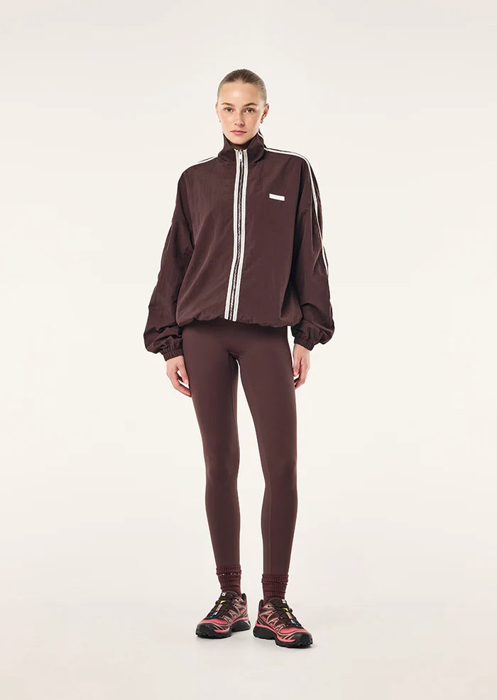 model wearing matching pants P.E Nation Radius Jacket in Dark Plum - oversized funnel neck jacket with side stripe detail