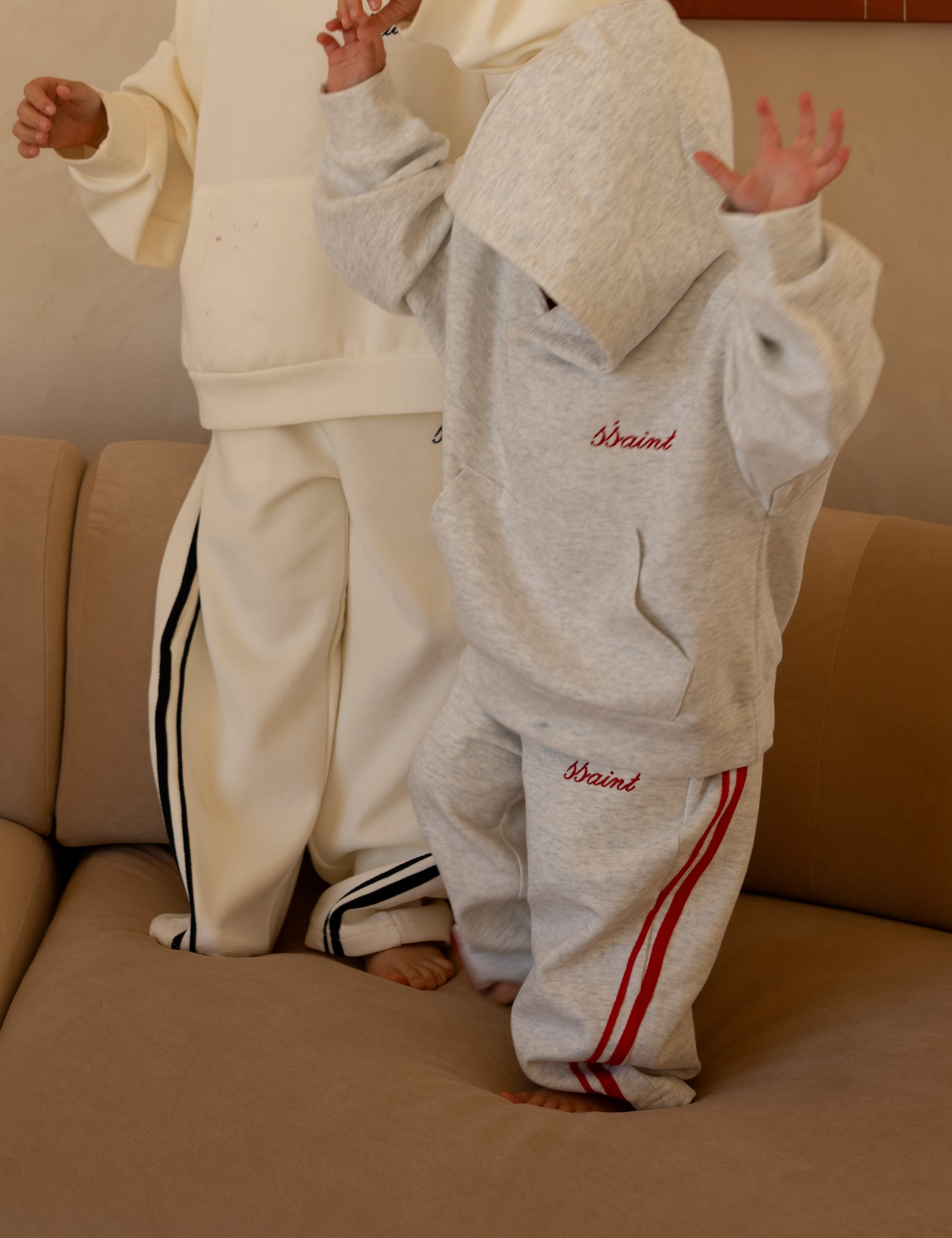 Child wearing ŚSAINT barrel-leg trackpant in grey and red colourway set