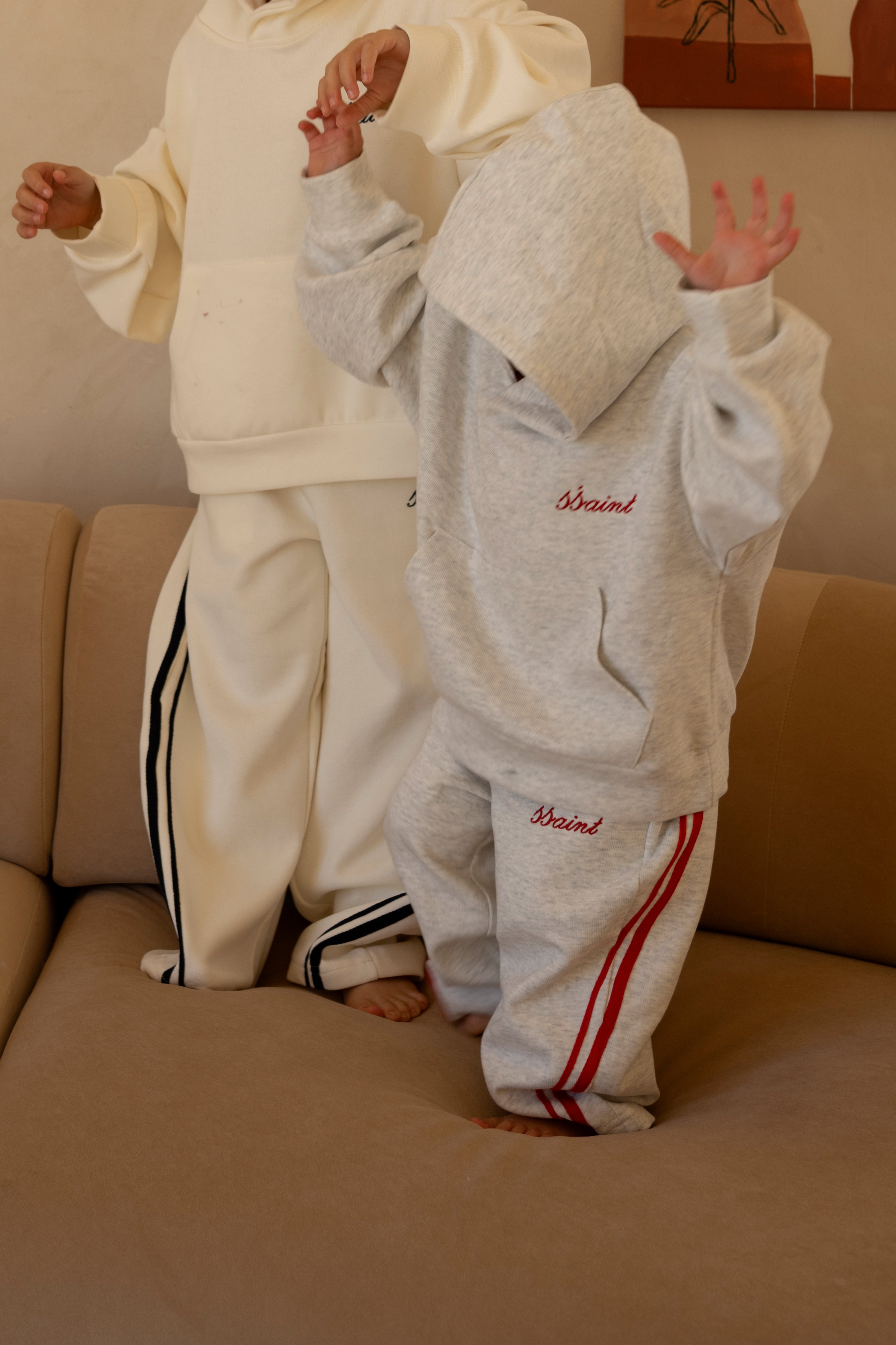 Child wearing ŚSAINT barrel-leg trackpant in grey and red colourway set