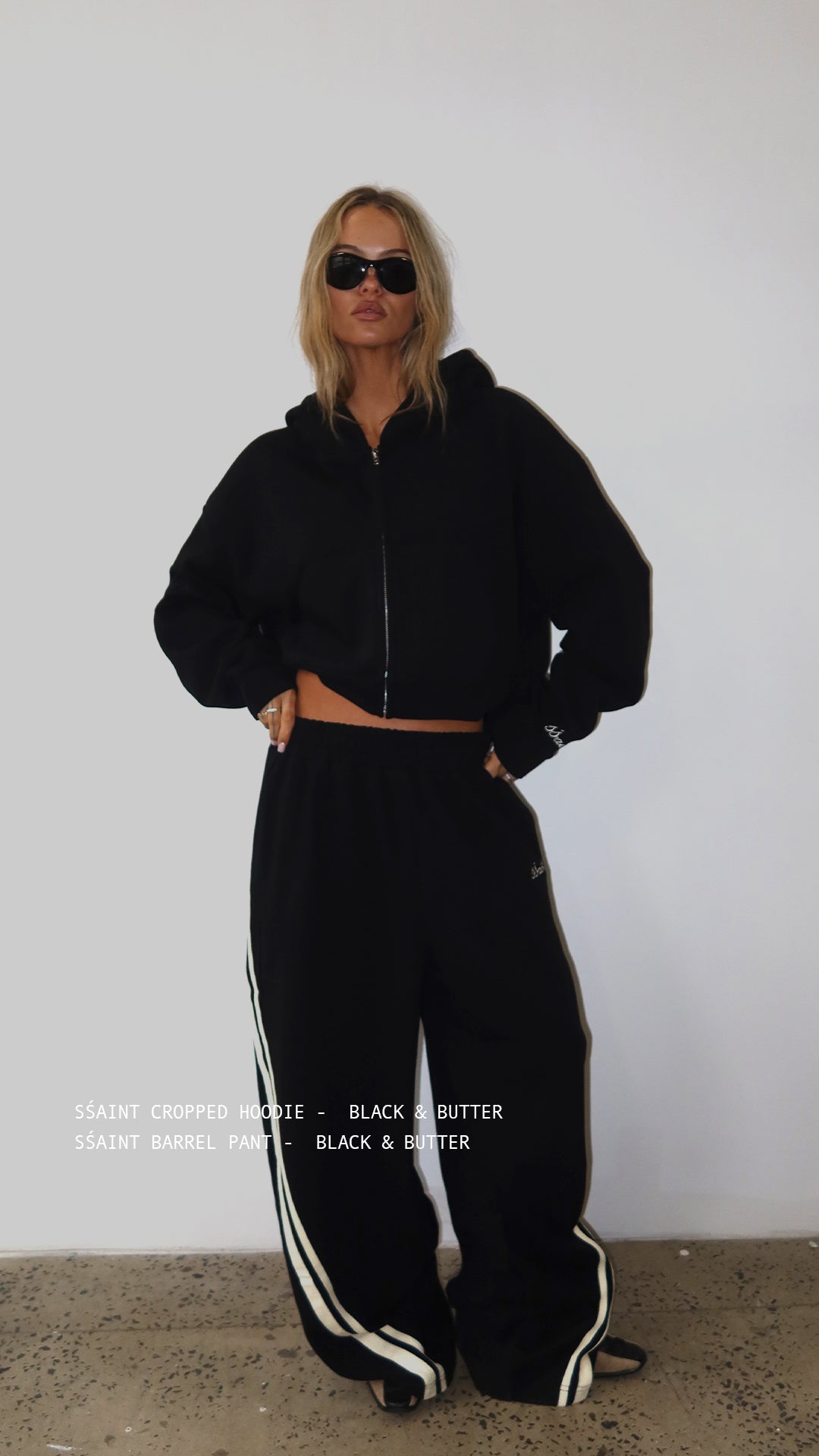 Woman wearing ŚSAINT black and butter cropped zip hoodie
