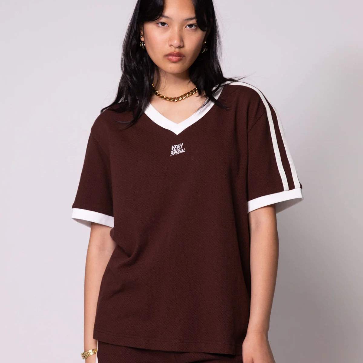 Woman wearing a brown outfit with white accents on a plain background