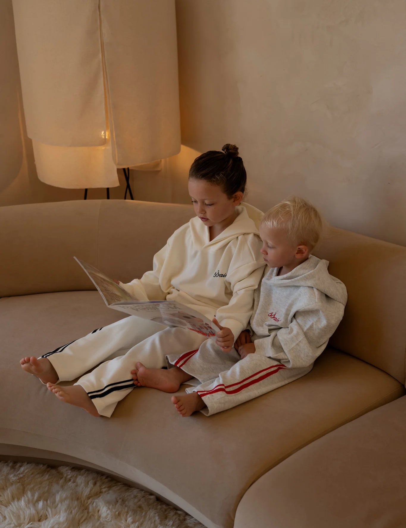 Matching kids cream SSAINT hoodie and track pant set worn indoors