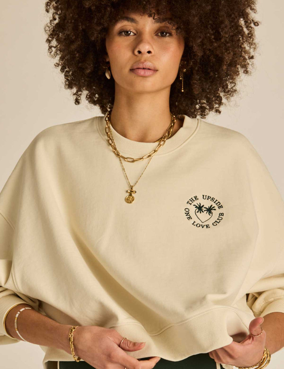 “The Upside Molokai Paloma Crew in cream, oversized organic cotton sweatshirt with embroidered green palm tree logo.”