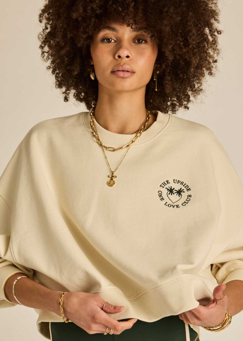 “The Upside Molokai Paloma Crew in cream, oversized organic cotton sweatshirt with embroidered green palm tree logo.”