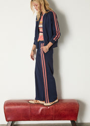 Woman wearing a navy tracksuit with pink stripes on a white background