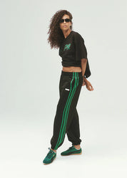 PE Nation Clarity Trackpant in black with green contrast side stripe, side view