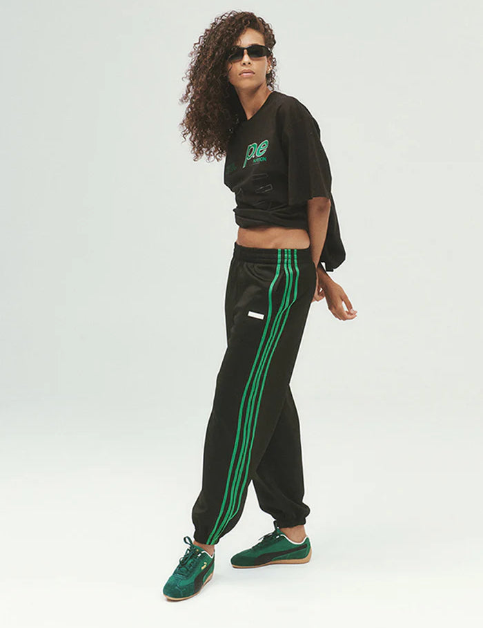PE Nation Clarity Trackpant in black with green contrast side stripe, side view