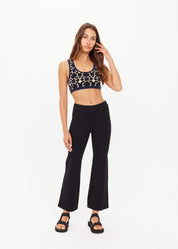 Woman wearing a patterned crop top and black flared pants on a white background