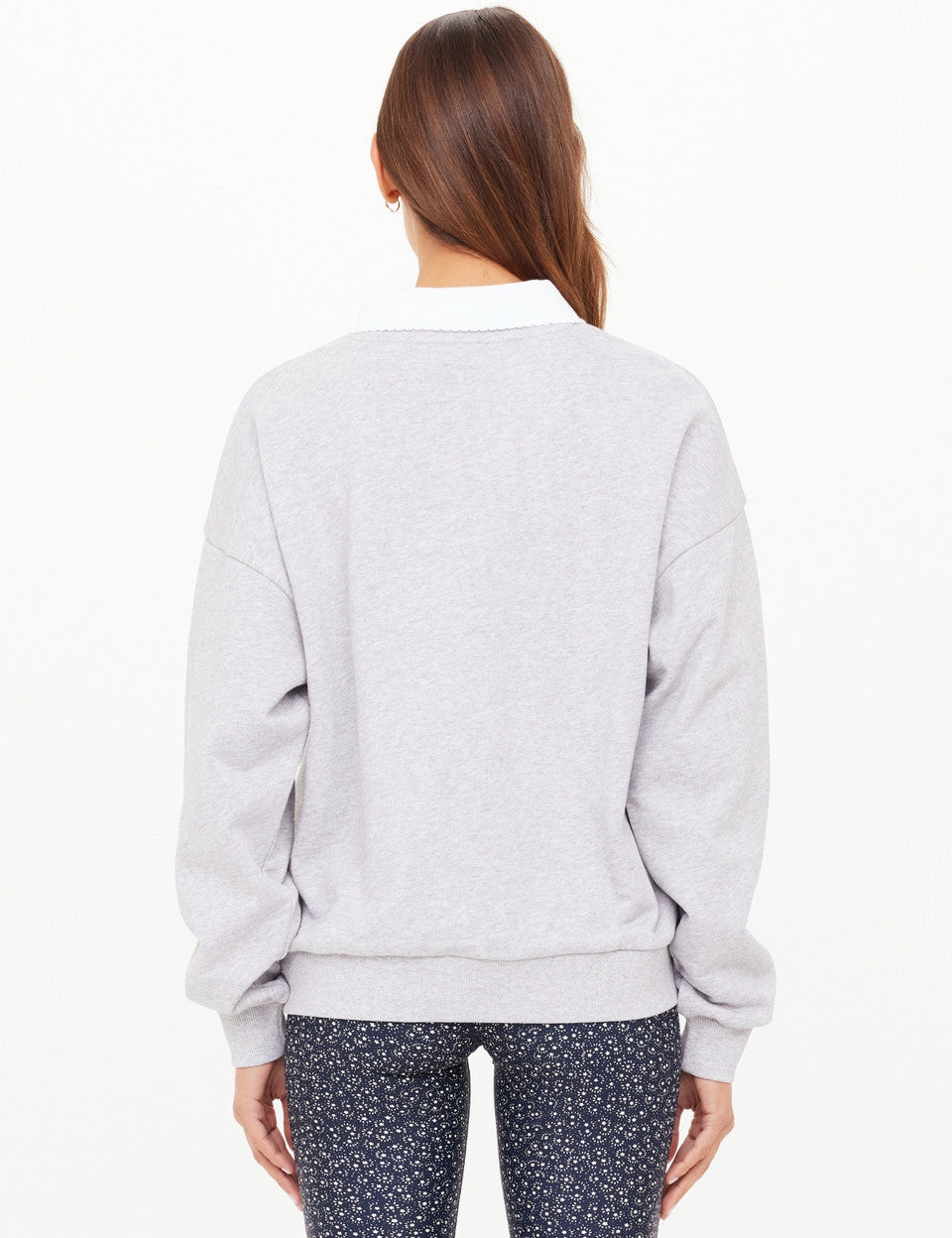 Person wearing a light gray sweatshirt with a white collar on a white background