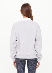 Person wearing a light gray sweatshirt with a white collar on a white background